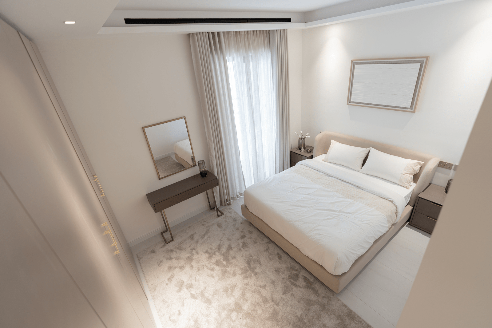 Bedroom with a dresser and mirror, decorated in a neutral color scheme.